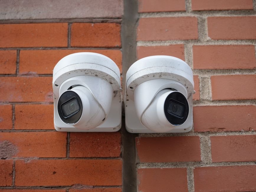 Comparatif visuel de deux détecteurs extérieurs différents (IR simple et double technologie) installés sur une maison, pour choisir la meilleure solution contre les fausses alertes