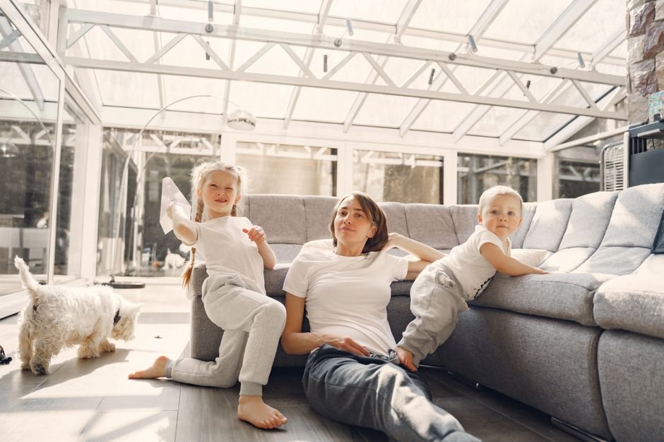 Famille française dans un salon contemporain observant un détecteur de fumée connecté au plafond, illustrant la protection offerte par une alarme maison